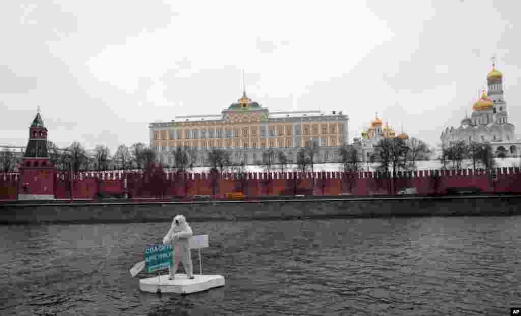 A Greenpeace activist, dressed as a polar bear sits on a wooden block of "ice" on the Moskva River near the Kremlin, protests against plans for oil drilling in the Arctic, in Moscow, Russia.