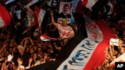 ພວກທີ່ສະໜັບສະໜຸນ ທ່ານ Mohamed Morsi ປະທານາທິບໍດີ​ອີຈິບທີ່ຖືກໂຄ່ນໄປນັ້ນ ຖືທຸງຊາດຜືນໃຫຍ່ ໃນຂະນະທີ່ຮ້ອງຄໍາຂວັນ ຕໍ່ຕ້ານນາຍພົນ Abdel-Fattah el-Sissi ລັດຖະມົນຕີກະຊວງປ້ອງກັນປະເທດ ຢູ່ນອກວັດອິສລາມ Rabaah al-Adawiya ຢູ່ຄຸ້ມ Nasr ໃນກຸງໄຄໂຣຂອງອີຈິບ ໃນວັນທີ 2 ທັນວ 2013 ຜ່ານມານີ້. 