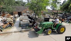 Justin Schultz uses a tractor to help remove debris from neighbors' homes destroyed by floodwaters in the aftermath of Hurricane Harvey, Sept. 3, 2017, in Spring, Texas.