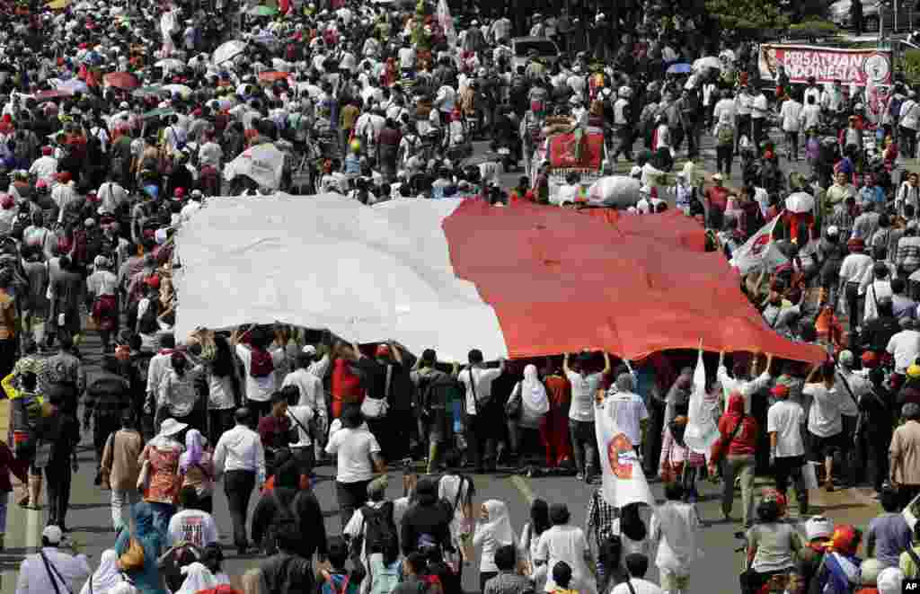 Supporters of Indonesian President Joko Widodo carry a large Indonesian flag during a parade following his inauguration in Jakarta, Indonesia, Oct. 20, 2014.