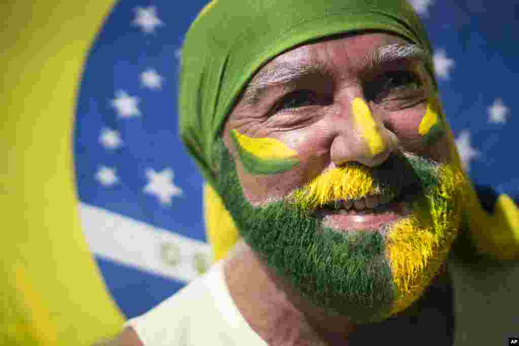 A protester with his face painted holds a flag during a protest at Copacabana beach in Rio de Janeiro. Anti-government demonstrators began streaming into the streets of cities throughout Brazil on Sunday to demand the impeachment of President Dilma Rousseff.