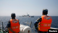 FILE - Officers of the Vietnamese Marine Guard monitor a Chinese coast guard vessel, top, on the South China Sea, about 210 km (130 miles) offshore of Vietnam, May 15, 2014.