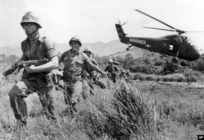 FILE - In this April 28, 1965 file photo, U.S. Marine infantry stream into a suspected Viet Cong village near Da Nang in Vietnam during the Vietnamese war. Filmmaker Ken Burns said he hopes his 10-part documentary about the War, which begins Sept. 17, 2017 on PBS, could serve as sort of a vaccine against some problems that took root during the conflict, such as a lack of civil discourse in America. (AP Photo/Eddie Adams, File)