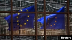 FILE - A European Union flag is reflected in a building of the EU headquarters in Brussels. 