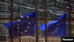 A European Union flag reflects on a building of EU headquarters in Brussels. The EU announced on Thursday, July 10, 2014 that it is imposing sanctions on South Sudanese officials who it says have been obstructing peace.