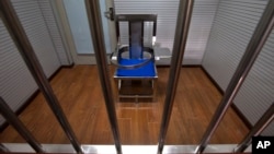 FILE - A chair specially designed to restrain inmates is seen behind bars in an interrogation room at the Number One Detention Center in Beijing, Oct. 25, 2012.