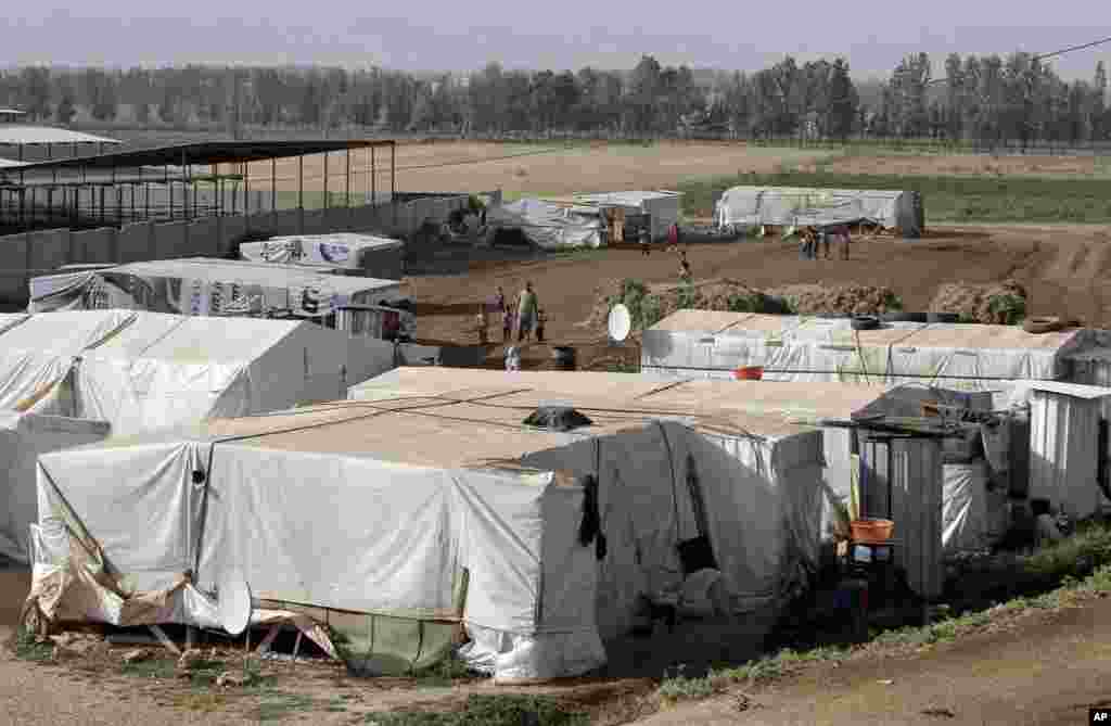 Syrian refugees walk outside their tents, at a Syrian refugee camp in the eastern Lebanese town of Majdal Anjar, Lebanon, June 19, 2014.