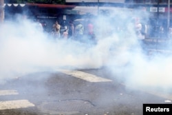 People run away from tear gas during riots for food in Caracas, Venezuela, June 2, 2016.