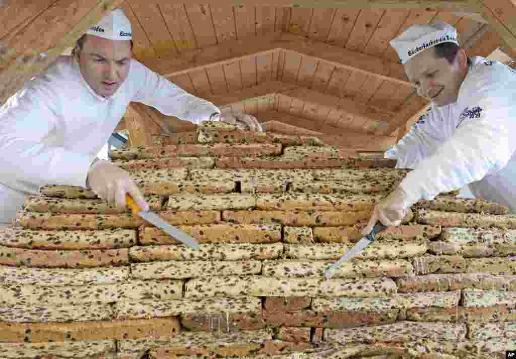 Bakers Dirk Willkomm, left, and Torsten Richter, right, members of the Association Dresden Stollen, work on a giant Stollen, a traditional Christmas cake, in Dresden, Germany.