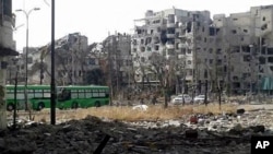 This May 7, 2014 photo provided by the Coordination Committee of Khalidiya Neighborhood in Homs shows green buses carrying Free Syrian Army fighters leaving Homs, Syria.