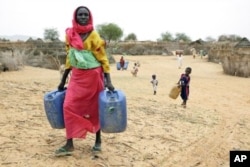 Darfur woman carries water.