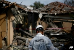 Un policía israelí inspecciona el daño a una casa afectada por un cohete en Mishmeret, centro de Israel, el lunes, 25 de marzo de 2019.