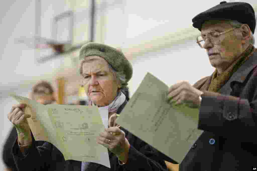 Dois eleitores observam os boletins de voto antes de entrarem na cabine de voto, em Bucareste, Roménia. Os romenos foram a votos este Domingo, 2, para eleger um novo Presidente, que vai substituir Traian Basescu, no poder há 10 anos.&nbsp; Nov. 2, 2014 