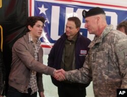 FILE - Fort Hood commander Lt. Gen. Robert Cone, right, greets singer Nick Jonas, left, as actor Gary Sinise looks on at a USO Community Strong event in Fort Hood, Texas.