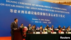 FILE - China's Finance Minister Lou Jiwei (L) gives a speech with the guests of the signing ceremony of the Asian Infrastructure Investment Bank at the Great Hall of the People in Beijing, Oct. 24, 2014. 