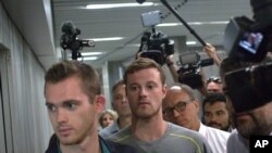 Le nageur américain Gunnar Bentz (gauche), et Jack Conger (centre), entourés par les medias, sortant du commissariat de l'aéroport de Rio, 18 aout, 2016. 