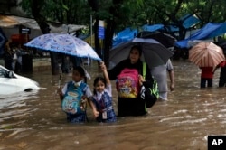 School children wade through a waterlogged street following heavy rains in Mumbai, India, Aug. 29, 2017.