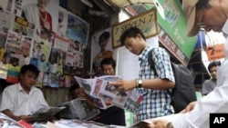 Customers buy local weekly journals at a roadside shop in Rangoon, Burma, Aug. 20, 2012. 