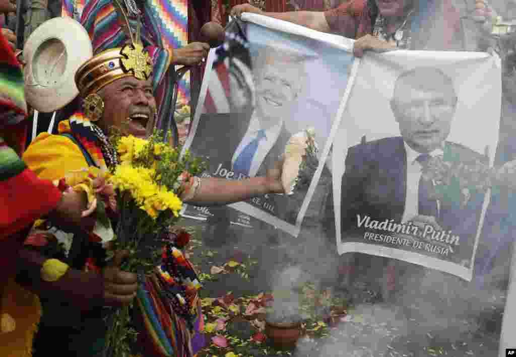Shamans hold photos of U.S. President Joe Biden and Russia&#39;s President Vladimir Putin during a year-end ritual where they predict political and social issues expected to occur in the next year, in Lima, Peru, Dec. 29, 2021.