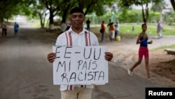 U.S. citizen William Potts poses with sign that says "USA my racist country" in Spanish, Havana, Cuba, Oct. 25, 2013.
