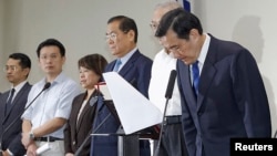 Taiwan President Ma Ying-jeou, right, bows during a news conference with party officials after the ruling Kuomintang (KMT) party was defeated in the local elections in Taipei, Nov. 29, 2014. 
