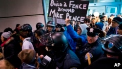 Los manifestantes, rodeados de policías y viajeros, pasaron por una salida de la Terminal 4 del Aeropuerto Internacional John F. Kennedy en Nueva York, el sábado 28 de enero, luego de que dos refugiados iraquíes fueran detenidos mientras trataban de entrar el país.