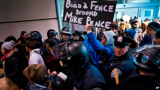 Los manifestantes, rodeados de policías y viajeros, pasaron por una salida de la Terminal 4 del Aeropuerto Internacional John F. Kennedy en Nueva York, el sábado 28 de enero, luego de que dos refugiados iraquíes fueran detenidos mientras trataban de entrar el país.