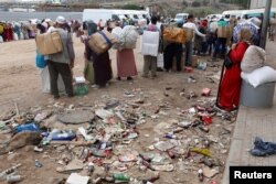 FILE - Moroccans queue with goods to be taken across the border from Spain's North African enclave of Melilla into Moroccan settlement of Beni Ansar, in Melilla, Spain, July 19, 2017.