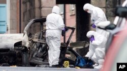 Police forensic officers inspect the aftermath of a suspected car bomb explosion in Derry, Northern Ireland, Jan. 20, 2019. 