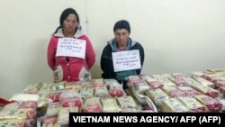 Bức hình chụp vào ngày 2 tháng 1, 2018 cho thấy cặp vợ chồng người H'mong đằng sau 489 bánh heroin mà họ định tuồn vào Việt Nam từ Lào tại một đồn cảnh sát (Hình: TTXVN/ AFP)