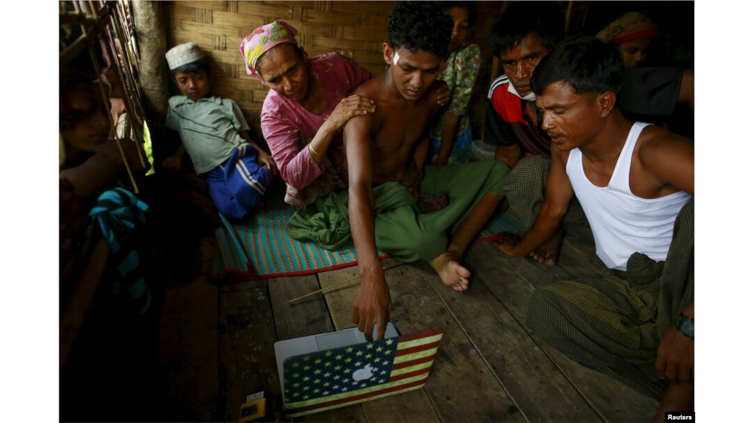 FILE - Abdhulami, center, 22, who was released from a human trafficking boat, points at pictures of people he recognises from the boat as he rests at a refugee camp outside Sittwe, Myanmar May 27, 2015. When the Myanmar navy seized the boat used by people smugglers.