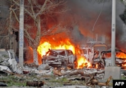 FILE - Wrecked cars burn at the scene of a terror attack at the Ambassador Hotel, after a car bomb exploded on June 1, 2016 at a top Mogadishu hotel that houses several MPs, killing several people, and followed by a gun battle.