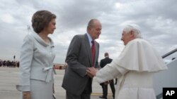 In this picture made available by the Vatican newspaper Osservatore Romano, Spain's King Juan Carlos, next to Queen Sofia welcomes Pope Benedict XVI upon his arrival at Madrid's Barajas airport, August 18, 2011