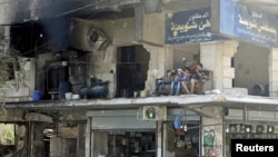 FILE - Residents sit on the balcony of a damaged building in Aleppo's al-Shaar neighborhood, Syria, Aug.1, 2015.