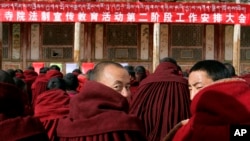 About 90 monks sit in front of a red banner that says: "Work Meeting for the Second Phase of Xicang Monastery's Rule of Law Propaganda Education Campaign," ahead of the re-education study session at the 200 year old Xicang Monastery in Luqu, China, Nov. 23, 2008.