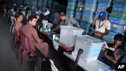 FILE - Afghan election commission workers sort ballots for an audit of presidential election results in front of international observers at an election commission office in Kabul, Afghanistan, Aug. 27, 2014.