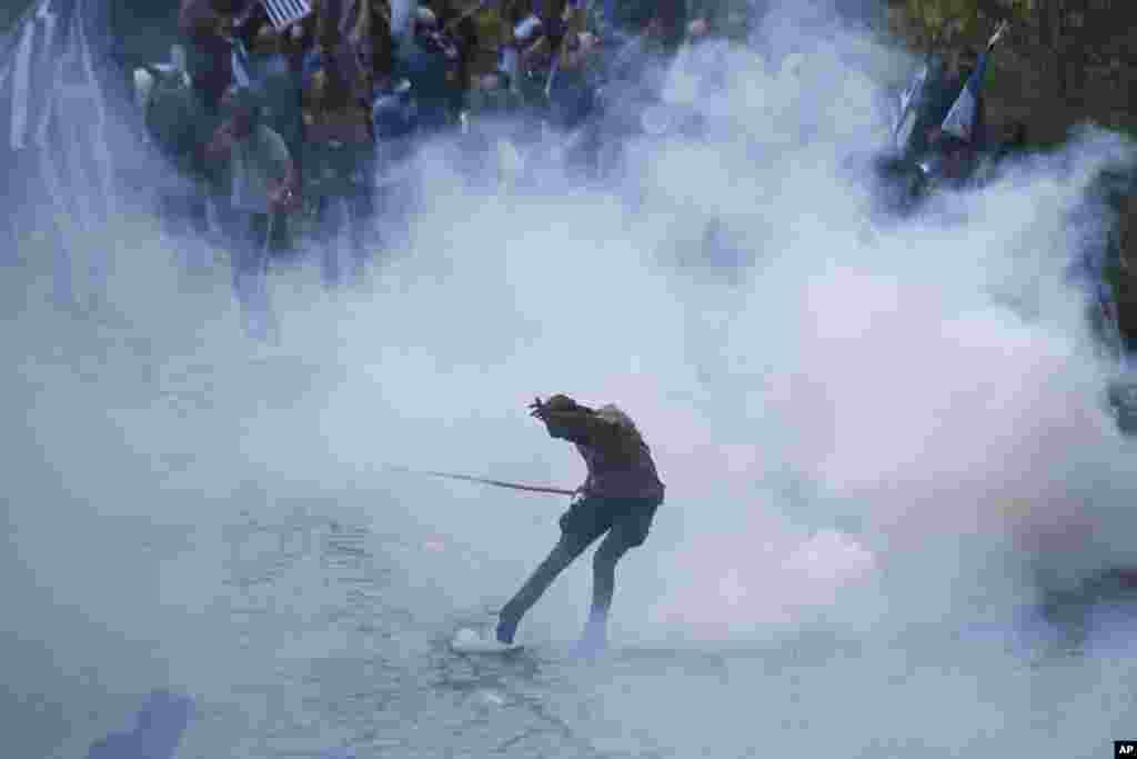 An opponent of the deal between Greece and Macedonia kicks a tear gas thrown by riot police during clashes at the village of Pisoderi near the border with Macedonia in northern Greece. The foreign ministers of Greece and Macedonia signed a preliminary accord to end a decade-long dispute by renaming Macedonia the Republic of North Macedonia. &nbsp;