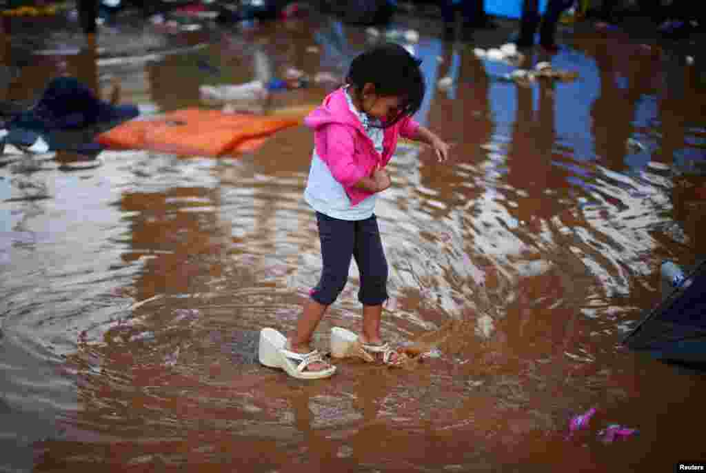 Rosa Julia Romero, a four-year-old migrant girl from Honduras, part of a caravan of thousands from Central America trying to reach the United States, wears her mother&#39;s shoes as she walks through a temporary shelter after heavy rainfall in Tijuana, Mexico, Nov. 29, 2018.