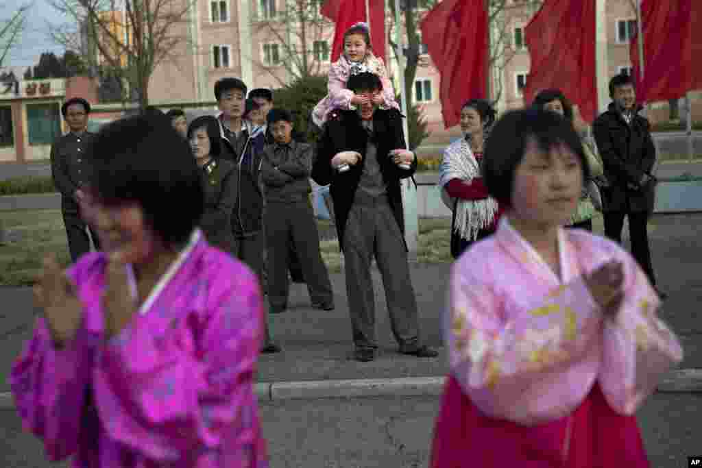 A North Korean child covers the eyes of her father as she sits on his shoulders watching mass folk dancing in front of Pyongyang Indoor Stadium, April 15, 2013. 