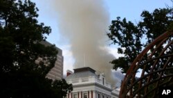 Smoke rises above the Houses of Parliament, behind the St. George's Cathedral, in Cape Town, South Africa, Jan. 2, 2022. 