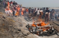 Devotees play Holi with ash and colors next to burning pyres at a cremation ground on the banks of river Ganges at the Manikarnika Ghat in Varanasi, India, Friday, March 6, 2020.