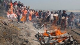 Devotees play Holi with ash and colors next to burning pyres at a cremation ground on the banks of river Ganges at the Manikarnika Ghat in Varanasi, India, Friday, March 6, 2020.