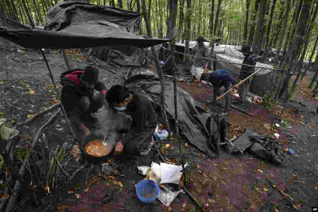 Migrants cook at a makeshift camp outside Velika Kladusa, Bosnia, Saturday, Sept. 26, 2020. Remote woods, abandoned run-down buildings and roadsides on the fringes of northwestern Bosnian towns are steadily filling with makeshift camps of migrants. (AP)
