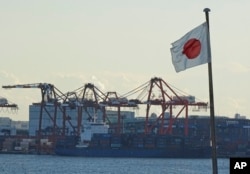 FILE - A Japanese flag is hoisted near the pier of a container terminal in Tokyo, Jan. 25, 2017. China is Japan’s biggest trading partner and more than 30,000 Japanese companies have operations in the country.
