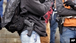 FILE - Men stand with pistols strapped at their sides at a gun rights rally on the steps of the Washington state capitol, Jan. 15, 2016, in Olympia, Wash.