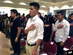 FILE - Long Chi Vong, center, 16, from Albuquerque, and other immigrants stand for the U.S. Pledge of Allegiance before taking the Oath of Citizenship at a ceremony in Rio Rancho, N.M., Aug. 19, 2016