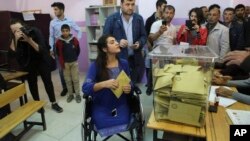 FILE - Lisa Calan, 28, who lost both her legs at an explosion, casts her vote in Diyarbakir, in Turkey's predominantly Kurdish southeast, Nov. 1, 2015. She is walking after receiving pioneering robotic surgery in Australia.