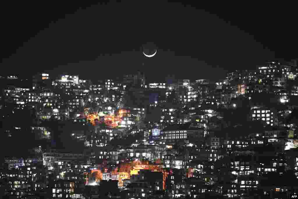 A crescent moon is seen over homes on a hillside in Aizawl, the capital of the northeastern Indian state of Mizoram.