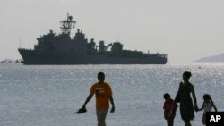 Một gia đình người Philippines đi dạo trên bãi biển tại Vịnh Subic. Phía sau là chiến hạm USS Harpers Ferry của hải quân Hoa Kỳ. (Ảnh tư liệu chụp ngày 17/2/2006).