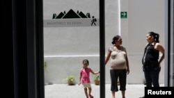 FILE - Salvadoran Yesenia Elizabeth Orellana, 40, who is pregnant, holds hands with her daughter Valentina, 3, as her friend Mirna Laines, also pregnant, looks on at the Catholic migrant shelter in San Luis Potosi.